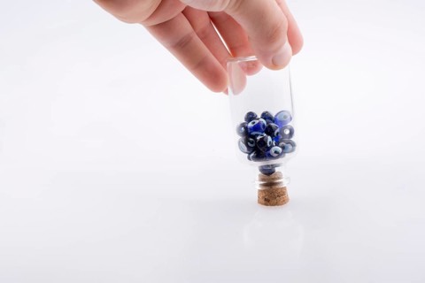Little glass bottle with blue evil eye bead in hand