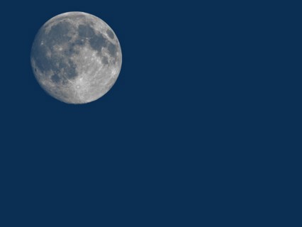 Full moon seen with telescope over blue with copy space