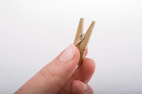 Hand holding a small wooden clothespin in hand