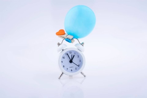 Alarm clock and a balloon with a heart on white background