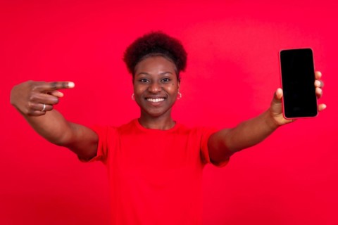 Young african american woman isolated on a red background with mobile pointing gesture