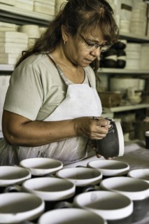 Craftswoman making the sgraffito on a piece of pottery