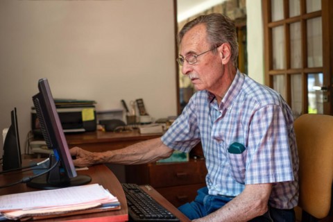 Older man sitting in front of his computer at home