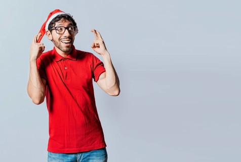 Guy with christmas hat making a wish on isolated background