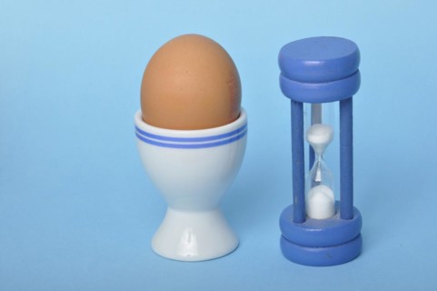 Boiled egg and hourglass on a blue background