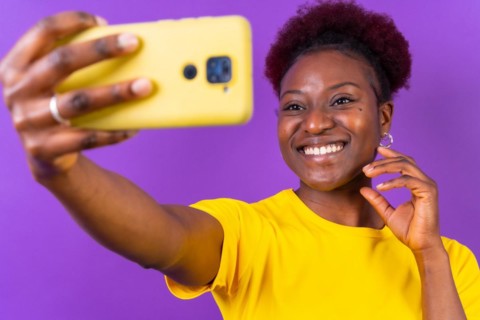 Young african american woman isolated on a purple background smiling and making a selfie
