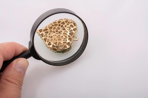 Heart shaped gold color metal under magnifying glass