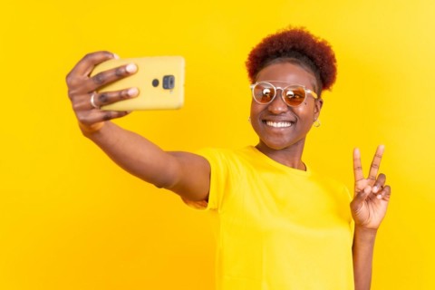 Young african american woman isolated on a yellow background smiling and making a selfie