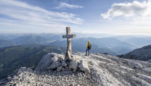 Mountaineer at a secondary peak of the Hochkoenig with summit cross