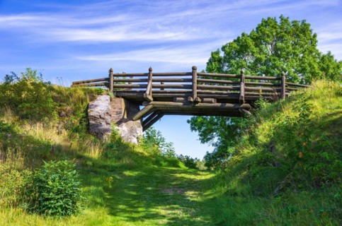Small wooden bridge over a field and hiking path in front of Laeckoe Castle at Lake Vaenern