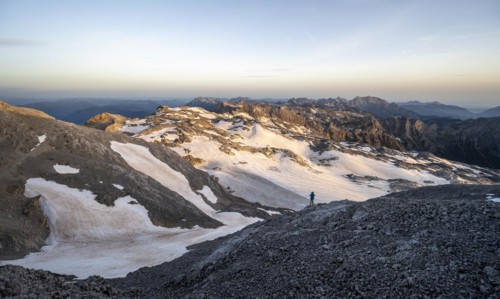 View of rocky plateau with snow and glacier at sunrise