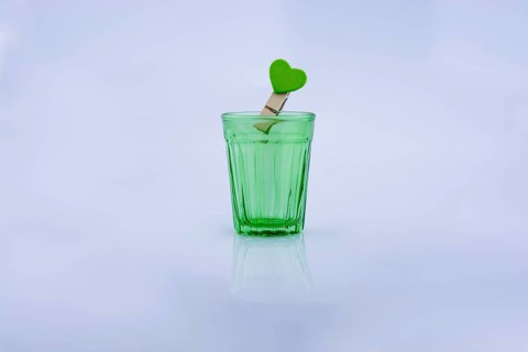 Drinking glass of gtreen color and a clothespin with a heart