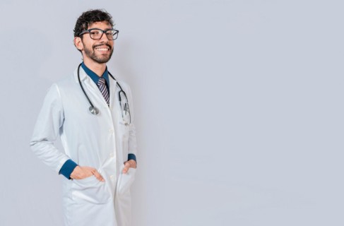 Portrait of happy doctor with hands in pockets isolated. Happy latin doctor with copy space isolated