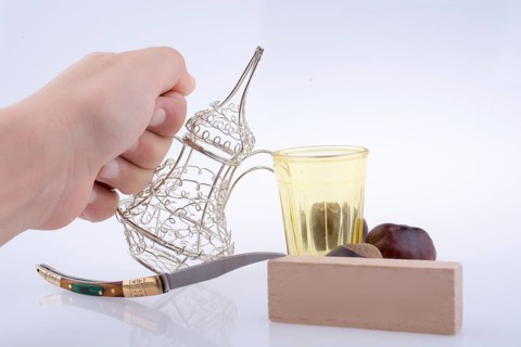 Silver color metal jug in hand a white background