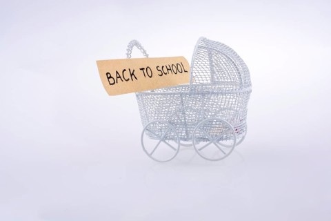 Toy baby carriage made of metal on white background has a sign
