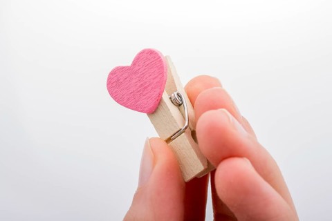 Heart shape icon attached to a clothespin in hand