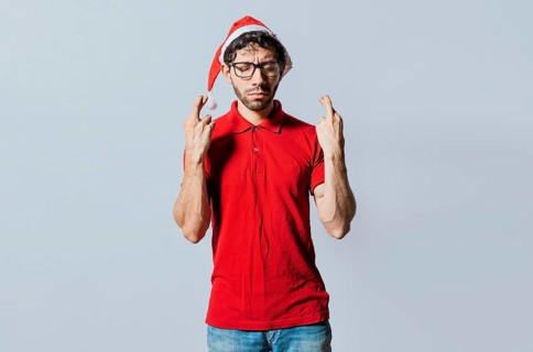 Handsome man in christmas hat making a wish on isolated background. Guy with christmas hat making a wish on isolated background