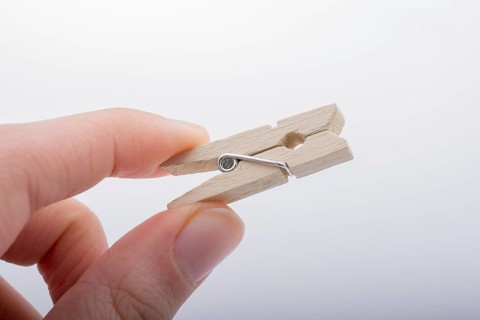 Hand holding a small wooden clothespin in hand