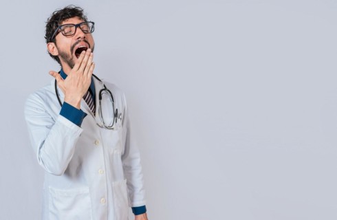 Young sleepy doctor yawning on isolated background. Tired of working doctor concept