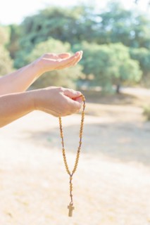 Woman's hands holding a Christian rosary with a cross