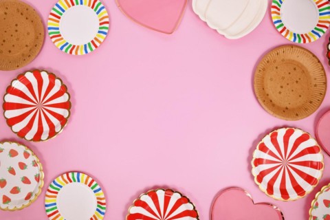 Colorful paper party plates forming border around pink background