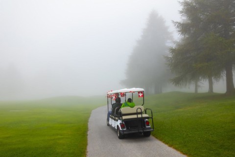 Golf cart with swiss flag on golf course with fog and trees in Crans Montana in Valais