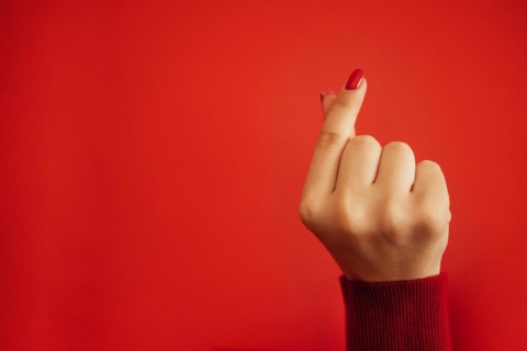 The Korean symbol for love is obvious. A woman's hand covers a heart. Place for text. Happy Valentine's day