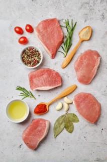 Overhead view of fresh pork escalopes with spice and herbs on concrete background