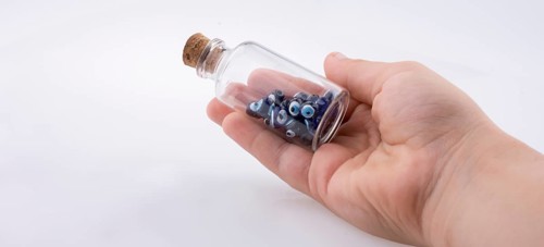 Little glass bottle with blue evil eye bead in hand