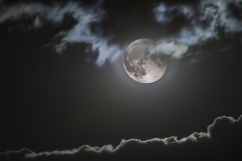 Rising full moon illuminates jagged cloud edge