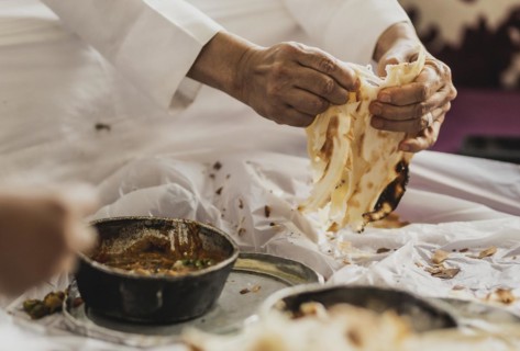 A man in traditional dress photographed with the Yemeni bread Malawach in Jeddah