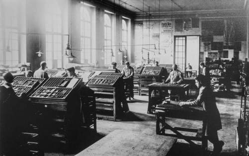 Early 20th century typesetters arranging types called typesetting for letterpress printing in print shop