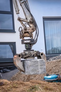 Excavator grab with stone on construction site
