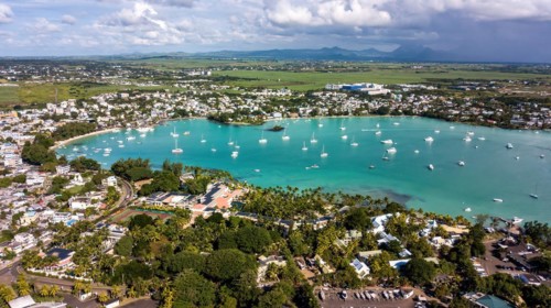Aerial view from bird's eye view of large sea bay Grand Baie with pleasure boats motor yachts sailboats anchored in sheltered bay