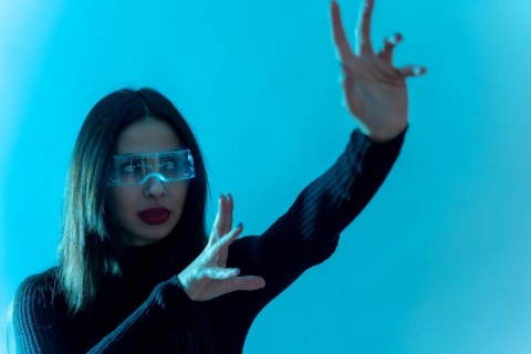 Metaverse technology concept. Woman in futuristic glasses on a blue background. Futuristic