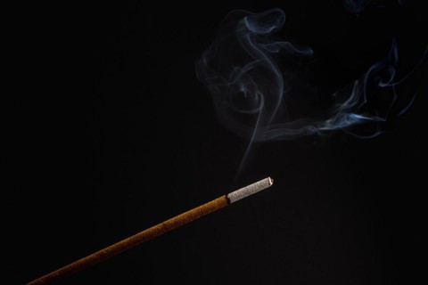 Burning incense stick smoldering on a black background