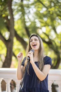 Young blonde woman singing in the street. Singer performing in the street