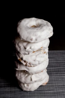 Sugar doughnuts glazed with icing sugar stacked in a pile on a black background and copy space