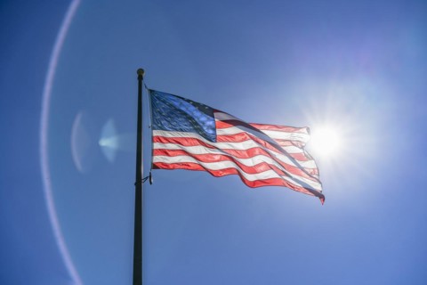 US flag waving in the wind. Vibrant colors over blue sky