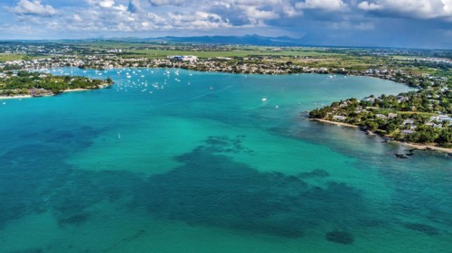 Aerial view from bird's eye view of large sea bay Grand Baie with pleasure boats motor yachts sailboats anchored in sheltered bay