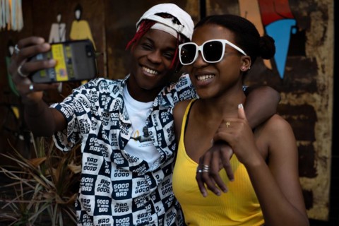 Young African-American couple taking a selfie and laughing. Friends with modern style having fun and posing