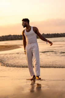 Portrait of black ethnic model enjoying summer vacation by the sea wearing a tank top