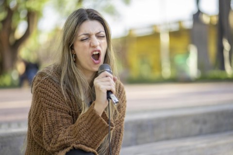 Young blonde woman singing in the street. Singer performing in the street