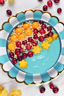 Blue fruit smoothie bowl dyed with natural spirulina powder decorated with cranberries