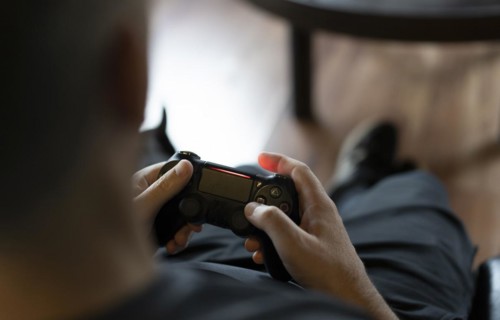 Close-up of an adult man's hands holding a joystick while playing a video game on a console. Copy space