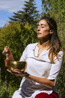 Woman playing a Tibetan singing bowl outdoors. Sound therapy