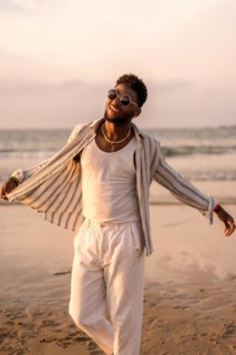 Portrait of attractive black ethnic man enjoying summer vacation by the sea feeling free