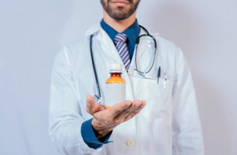 Doctor's hand holding a bottle of syrup. Doctor showing a bottle of syrup