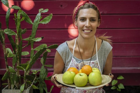 A woman carring a plateb full of fresh citrus and apples