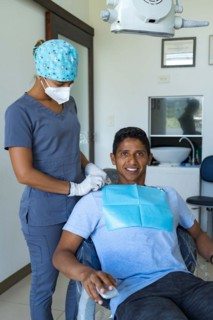 Female dentist in dental office talking with young male patient and preparing for treatment